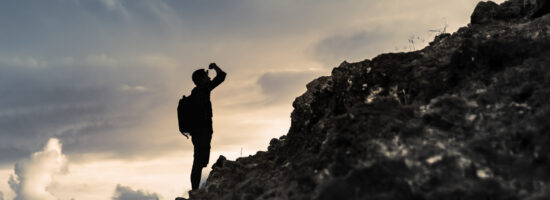 Man looking up mountain. Believe in yourself, overcoming challenges, pushing forward concept.